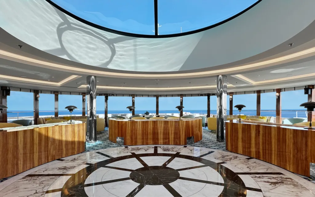 An observation lounge showing views to the ocean onboard the World Traveller cruise ship.